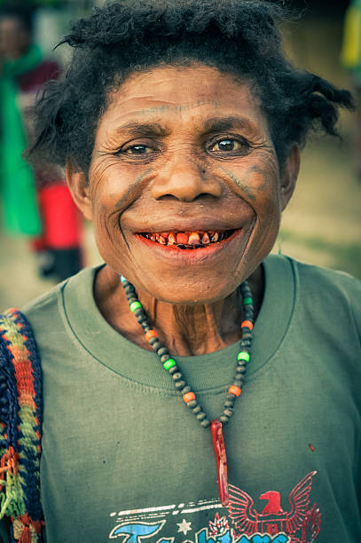 Will-will, Papua New Guinea - July 10 2015: Native woman with brown eyes and tattoos on her face wears necklace made of beads and smiles to photocamera in Will-will, Nuku, Papua New Guinea. Documentary editorial.