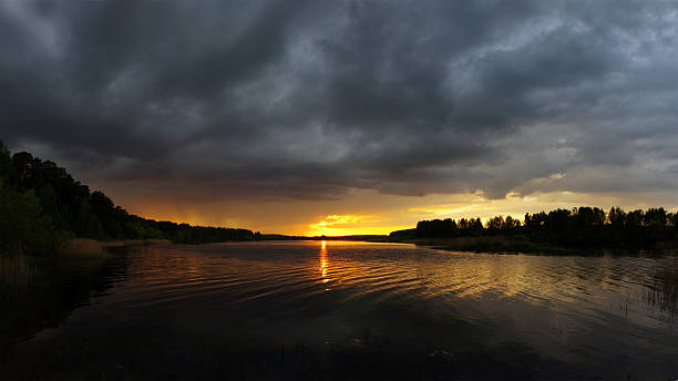 istock Evening sunset over golden lake, sun and clouds 530573690