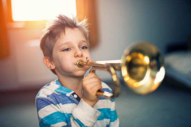 istock Little boy playing trumpet at home 530574308
