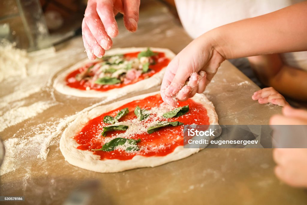 Preparing Pizza Margherita. Cooks hands Preparing Classical Pizza Margherita. Cooks add grated parmesan cheese. Selective focus Pizza Stock Photo