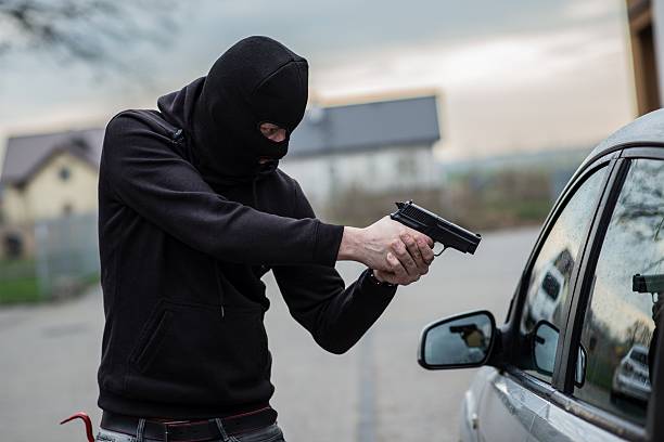 autodieb zeigt eine waffe in der fahrer - car stealing thief car thief stock-fotos und bilder