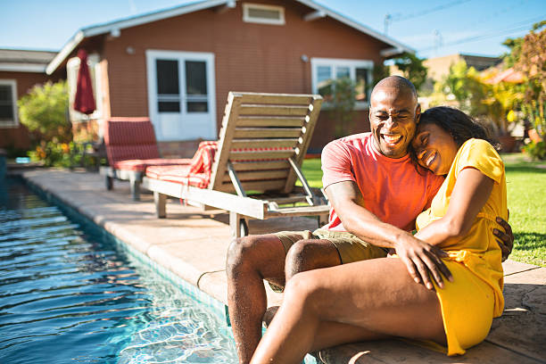 casal desfrutar africano em casa pátio na beira da piscina - swimming pool water people sitting imagens e fotografias de stock