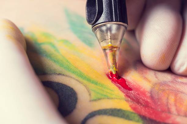Tattoo machine Male tattoo artist showing the process of making a tattoo on arm. Colorful tattoo art on human body and skin. Tattooist holding an active machine or gun. arm tattoo ideas for men pictures stock pictures, royalty-free photos & images
