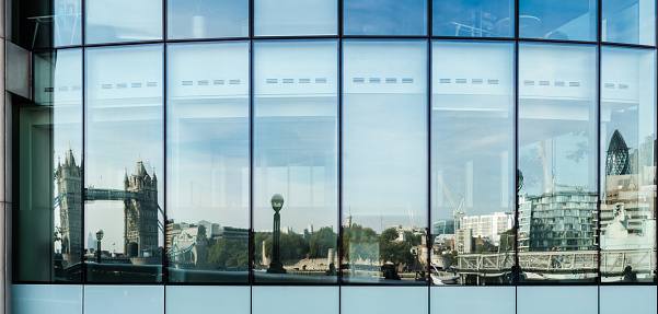 London, United Kingdom - September 28, 2014: The skyline of London from the Tower Bridge up to the modern buildings of the Financial District (the building of Swiss Re - aka the Gurkin - is located on the very right) is reflected in the windows of an office building on September 28, 2014 in London, UK.