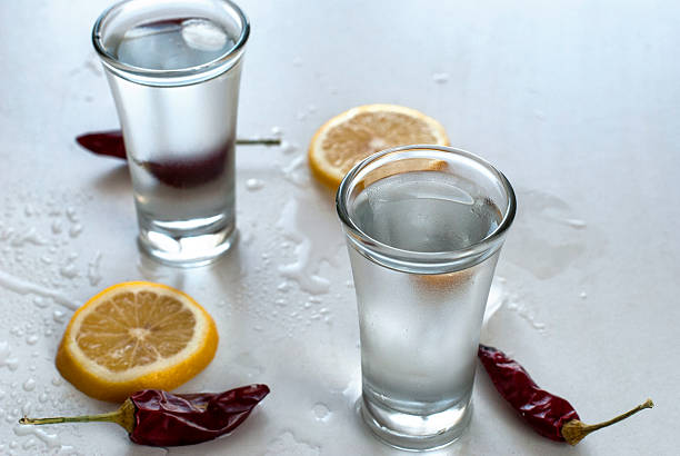 istock Cold vodka in a glass on a white wooden table 530583930