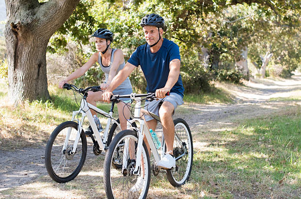 par ciclismo en el parque - action mature adult bicycle senior couple fotografías e imágenes de stock