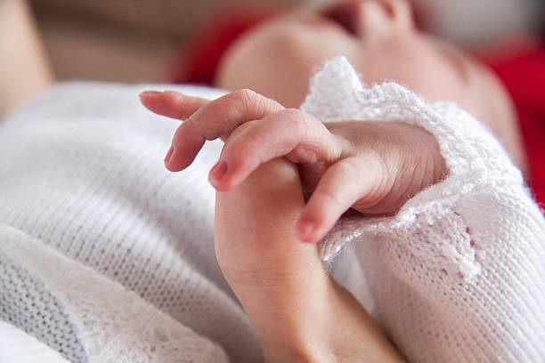 Baby holding female thumb stock photo