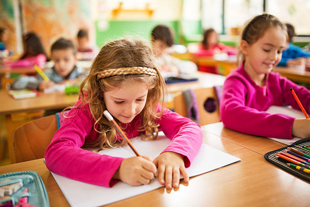 istock Schoolgirl writing in classroom. 530596827