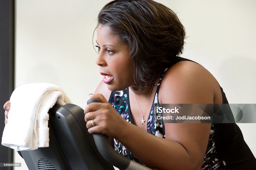 Black woman exercisng on a stationary bike in gym An attractive afro american woman is exercising in the gym.  She is on a stationary bike and has on a workout clothes.  Taken by a Canon 5D Mark 3 camera.  rm 20-29 Years Stock Photo