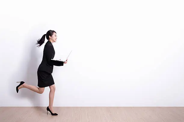 business woman running ,hold laptop computer with white wall background,great for design or text,