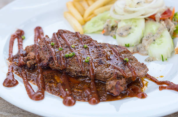 istock Grilled pork steak with vegetables salad on wood table 530617683