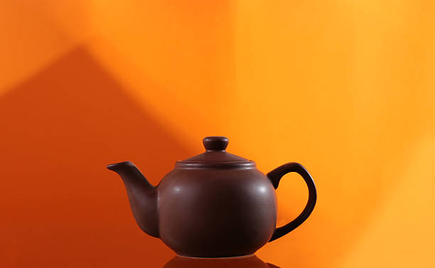 istock teapot from clay on an orange background with geometric pattern 530625333