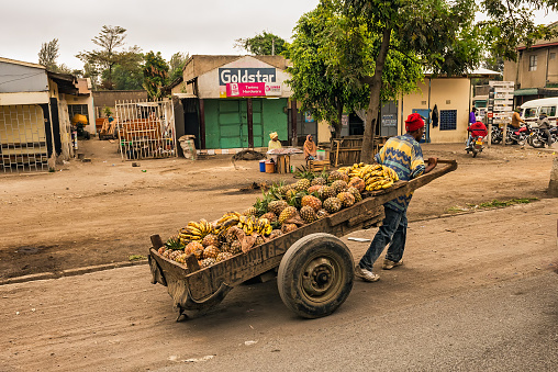 Arusha, Tanzania - October 21, 2014 : African man pulling a cart full of fruit in a shopping street of Arusha