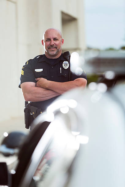 istock Happy police officer standing next to cruiser 530629061