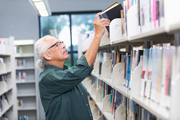 sênior homem hispânico na biblioteca - library student latin american and hispanic ethnicity university - fotografias e filmes do acervo