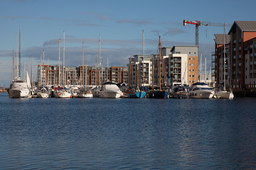 Portishead, England - December 27, 2014: Portishead Marina, North Somerset, Great Britain, sailing boats moored with a motor boat heading into the harbour. People can be seen on the harbour side. 