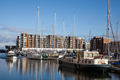 Portishead, England - December 27, 2014: Portishead Marina, North Somerset, Great Britain, sailing boats moored with a motor boat heading into the harbour. People can be seen on the boat and on the harbour. 