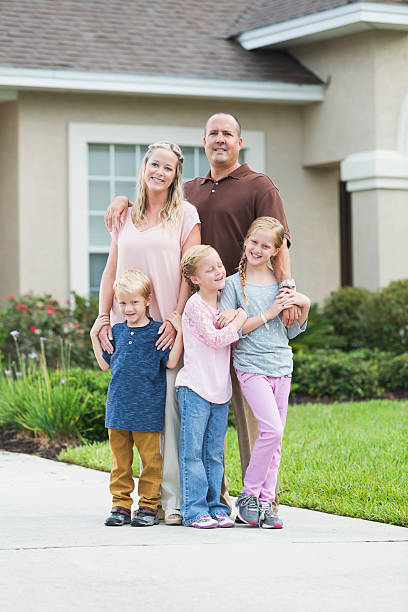 istock Family standing in front yard of home 530637383
