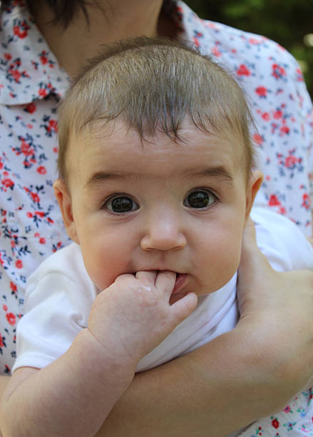 5 months old baby with fingers in her mouth