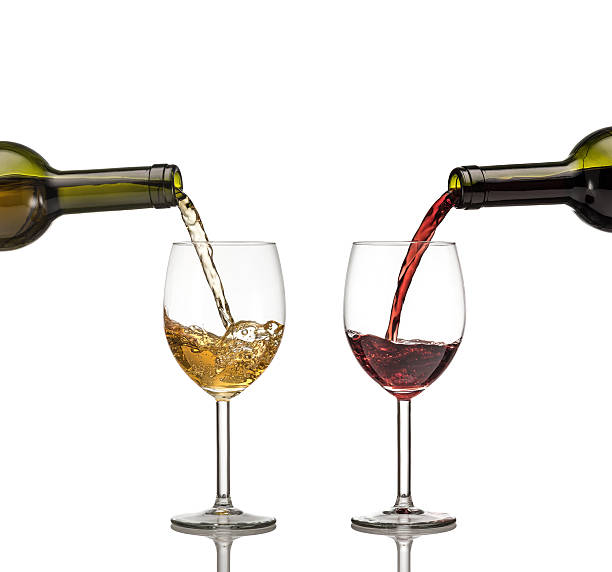 istock Red and white wine being poured into wine glass on white background 530640893