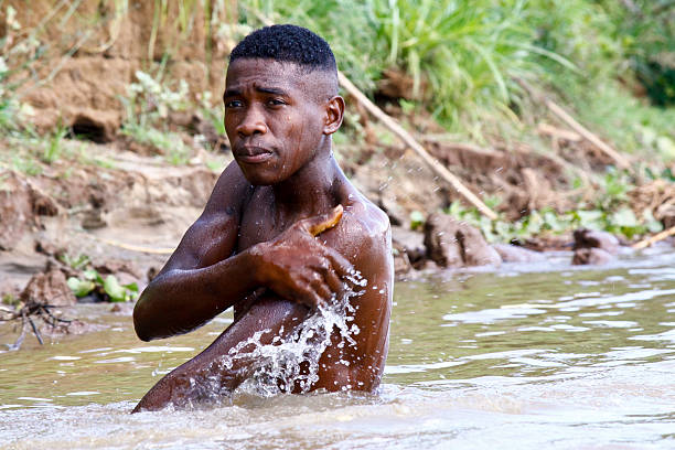 istock African poor man taking a bath in river, Madagascar 530649659