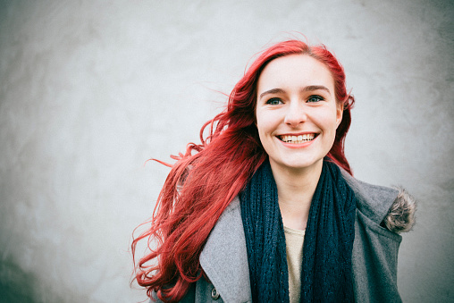 portrait of a young redhead female in front of a concrete wall