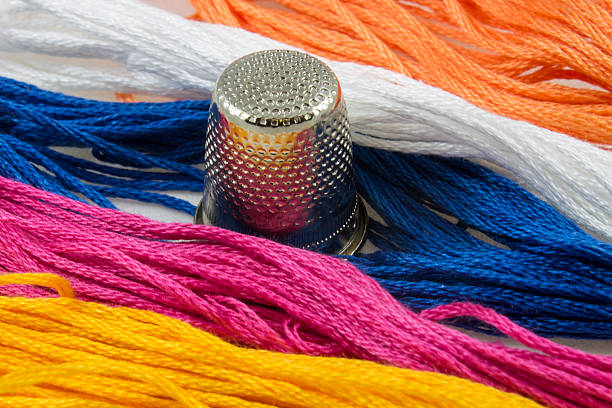strands of colored cotton and a thimble