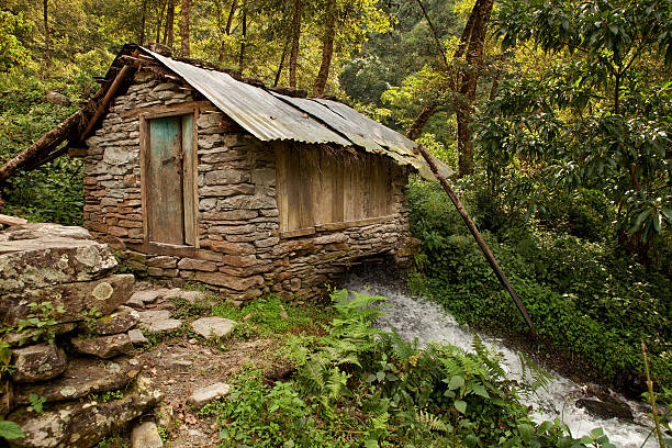 Chandrakot, Nepal - October 13, 2011: Water powered mill used to grind flour near Chandrakot which is approximately 45 kilometres West of Pokhara in Nepal.  In rural regions where electricity is not readily available or reliable old technology often works best.