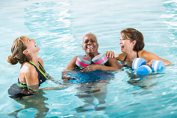 multirracial mulheres em água aula de exercício físico rir - fun senior adult aerobics exercise class imagens e fotografias de stock