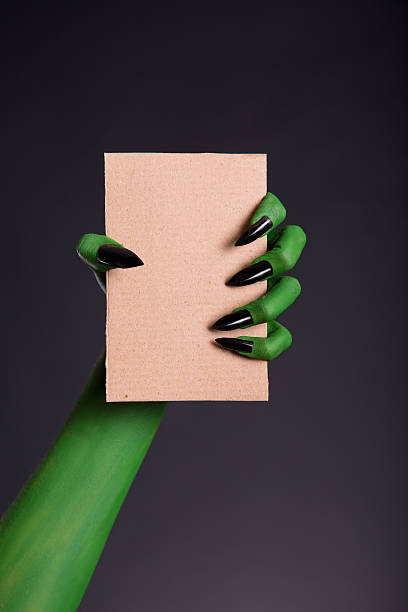 istock Green monster hand with black nails holding cardboard 530658651