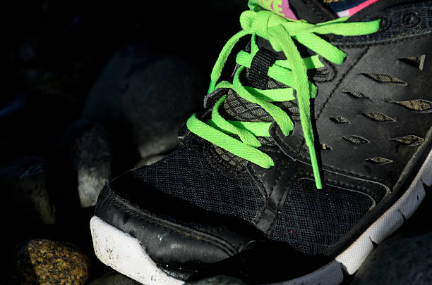 istock Black running shoe hitting the pebbles on a beach 530661199