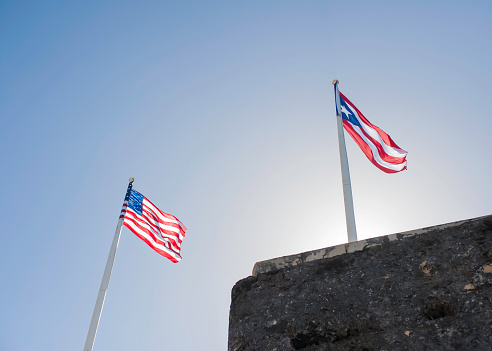 United States flag and Puerto Rican flags fly above the walls of Morro Castle in San Juan