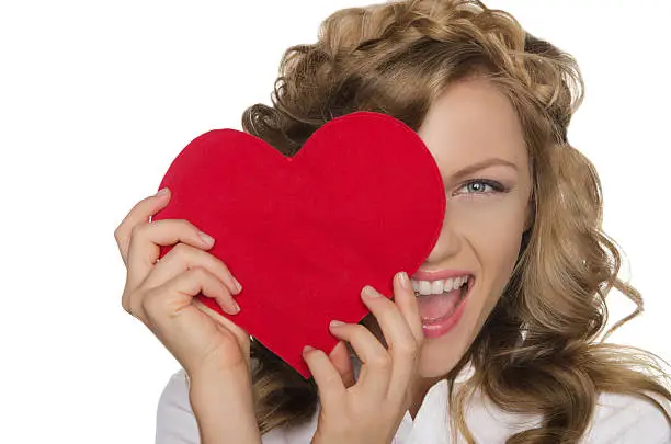 Photo of Smiling young woman holding heart in front of eye