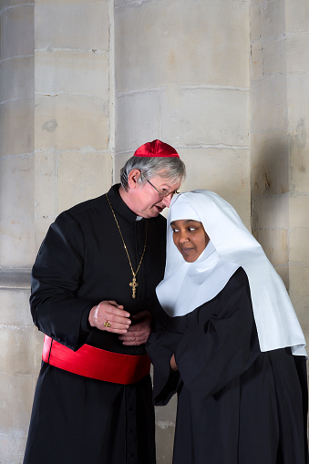 Catholic nun and cardinal talking in a medieval church
