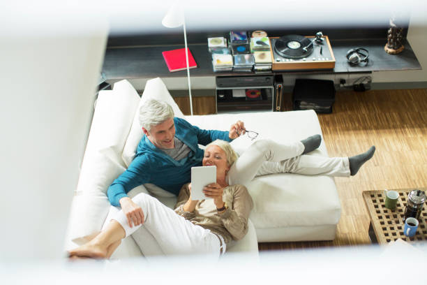 High angle view of older couple using digital tablet on sofa  chaise longue woman stock pictures, royalty-free photos & images