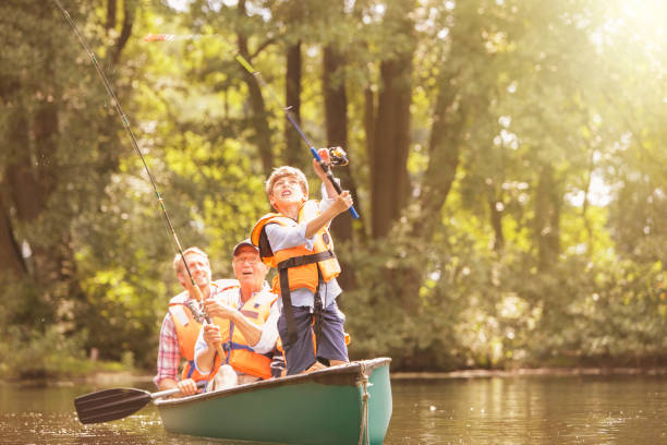 boy, father and grandfather fishing from canoe on lake - fishing active seniors family senior adult imagens e fotografias de stock