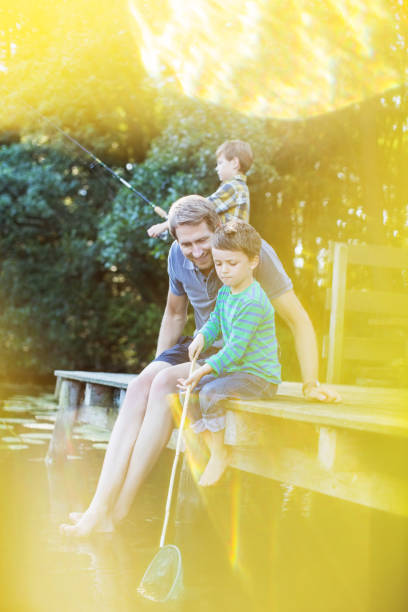 istock Father and sons fishing from dock 530682357