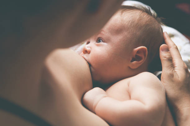 Mother holding and breast-feeding little baby stock photo