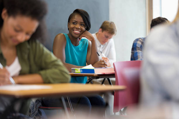 istock Smiling university student sitting at desk with hand on chin 530682853