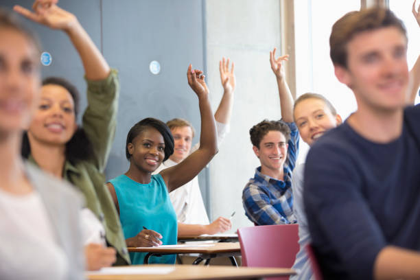 istock University students raising hands at seminar 530683017