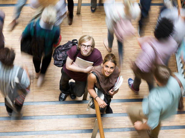 A group of cheerful college students walk together in a university hallway, engaging in conversation and laughter, signifying friendship and academic life.