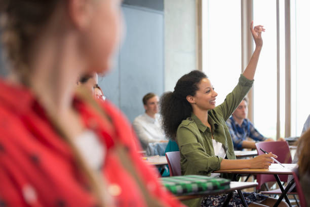 istock Female student raising hand during lecture with other students in background 530683199