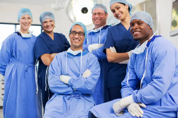 Photo of Group portrait of surgeons posing in operating theater
