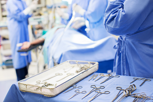Enfermera de pie junto a una bandeja con herramientas quirúrgicas en quirófano photo