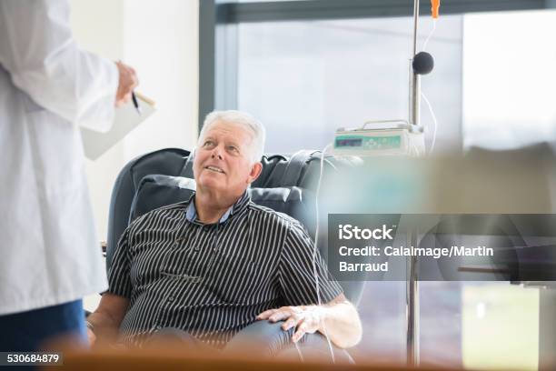 Doctor Talking To Patient Receiving Medical Treatment In Hospital Ward Stock Photo - Download Image Now