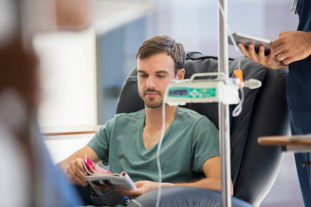 patient reading magazine, undergoing medical treatment in outpatient clinic - chemotherapy drug imagens e fotografias de stock