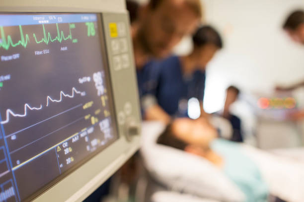 monitor de frequência cardíaca, paciente e médicos em experiência em unidade de terapia intensiva - emergency room - fotografias e filmes do acervo