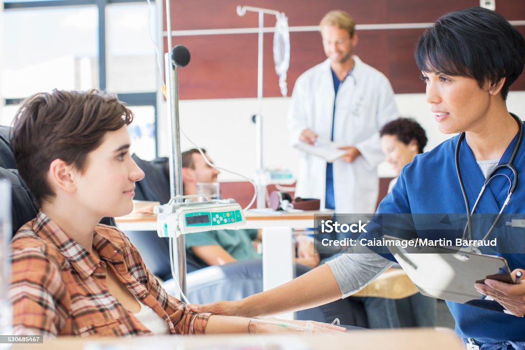 Female doctor holding clip board checking with female patient in outpatient clinic  Chemotherapy Drug Stock Photo