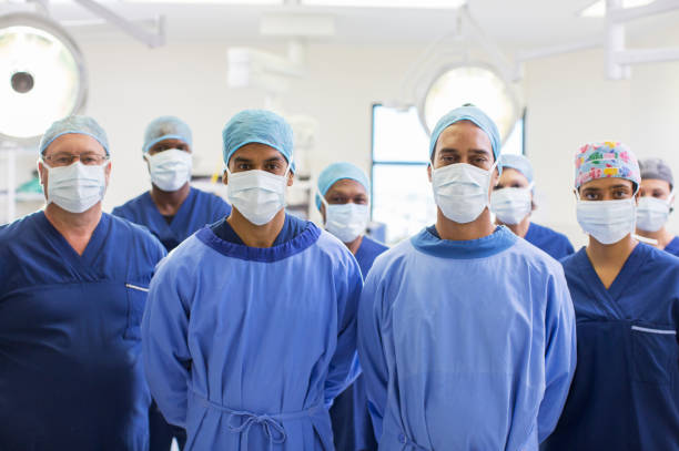 team von chirurgen im operationssaal - operationskittel stock-fotos und bilder