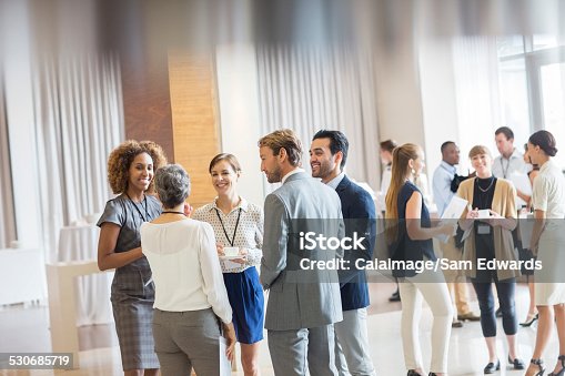 istock Group of business people standing in hall, smiling and talking together 530685719